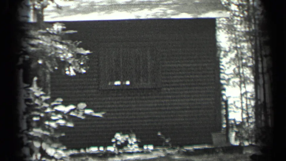 1939 Long Lake, Canada home-movie frame showing a wooded cabin exterior with horizontal siding and a small window.