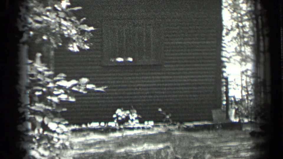 1939 Long Lake, Canada frame of a cabin side in the woods, with trees and a possible hand pump near the exterior wall.