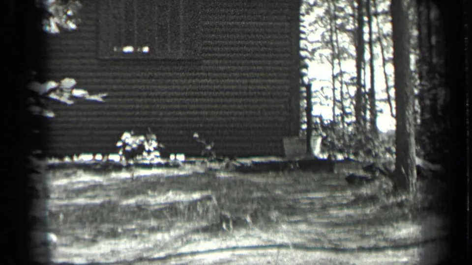 1939 Long Lake, Canada home-movie view of a cabin wall beside trees and open woodland ground.