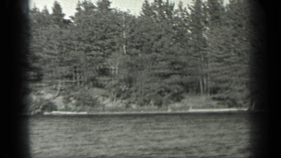 1939 Long Lake, Canada view of rippling water and a tree-lined shore seen through an 8mm film frame.