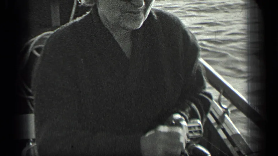 An adult passenger sits on a boat at Long Lake, Canada, with water and railing visible in grainy 1939 8mm footage.