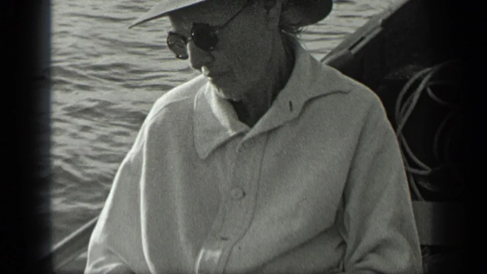1939 Long Lake home-movie frame of the seated man in sunglasses and a broad hat, filmed from close range on the fishing boat.