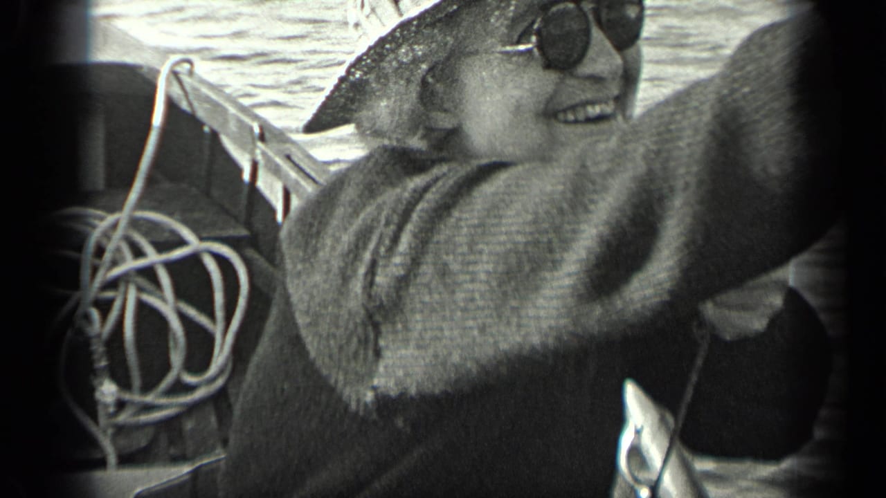 Smiling older woman in hat and sunglasses seated on a boat beside coiled rope.