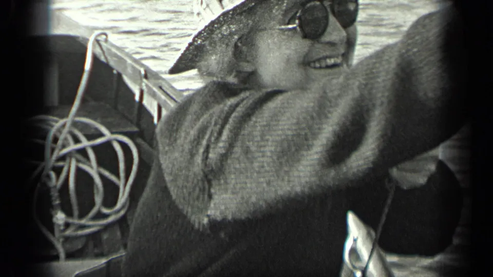 1939 Long Lake, Canada home-movie frame showing a smiling older woman in hat and sunglasses aboard a boat.