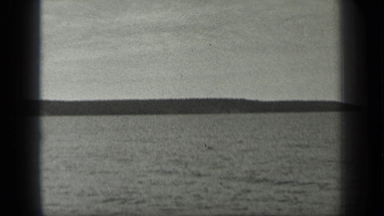 1939 Long Lake, Canada view across open water toward a low wooded shoreline, with soft focus and dark 8mm frame edges.