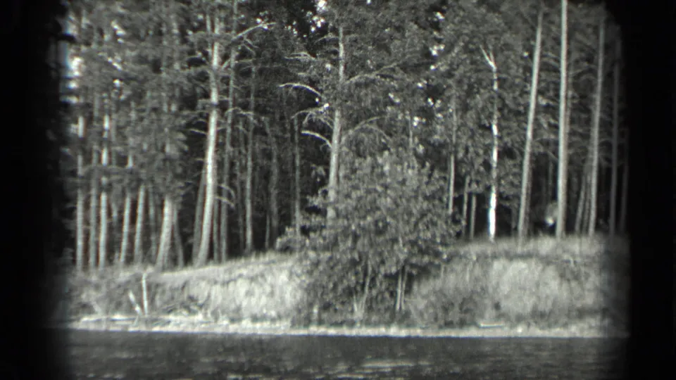 1939 Long Lake, Canada home-movie frame showing calm water, a forested bank, and tall trees along the shoreline.