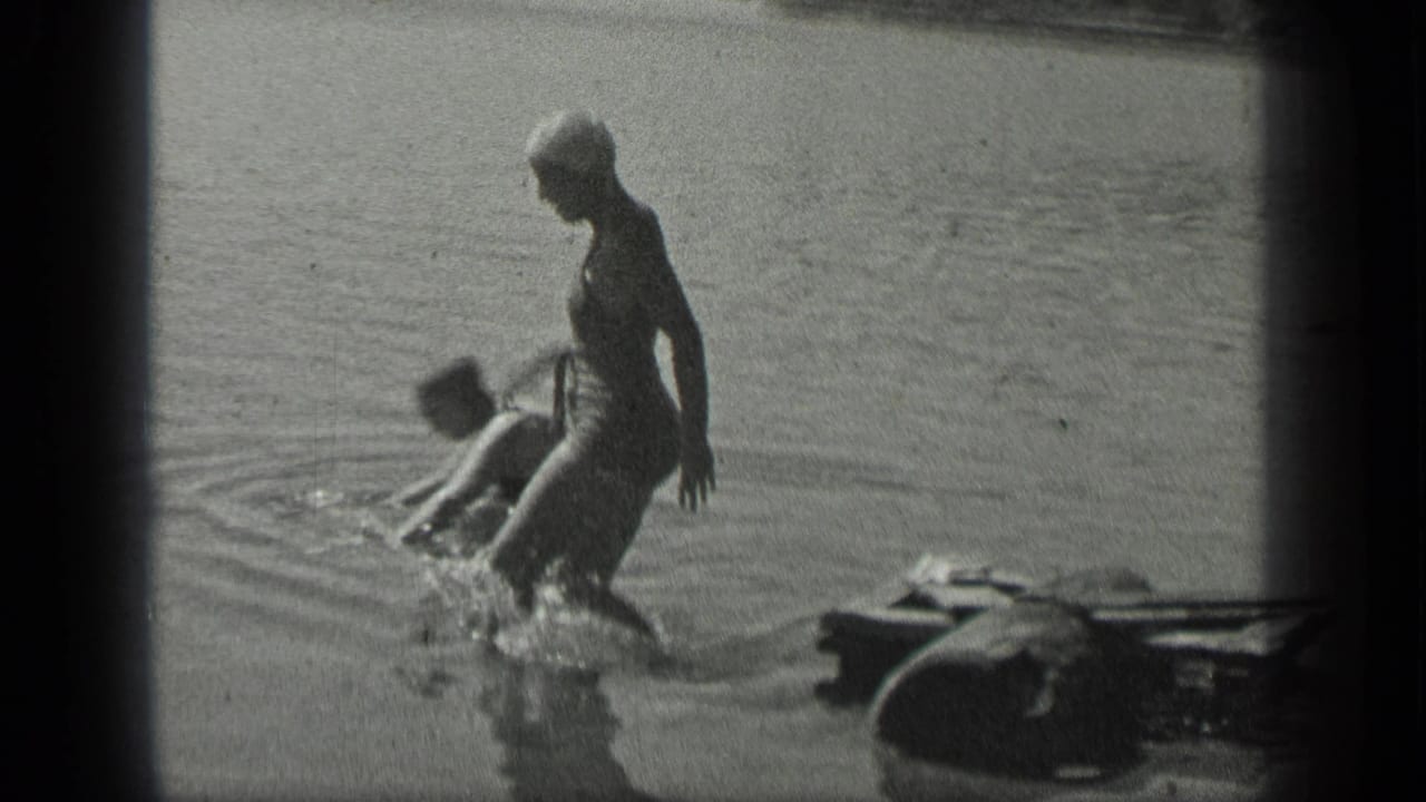 Woman steps into shallow lake water while another swimmer is nearby.