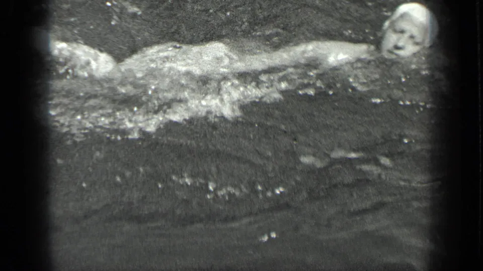A swim-capped figure extends an arm across the lake surface in this grainy 1939 Long Lake, Canada frame.
