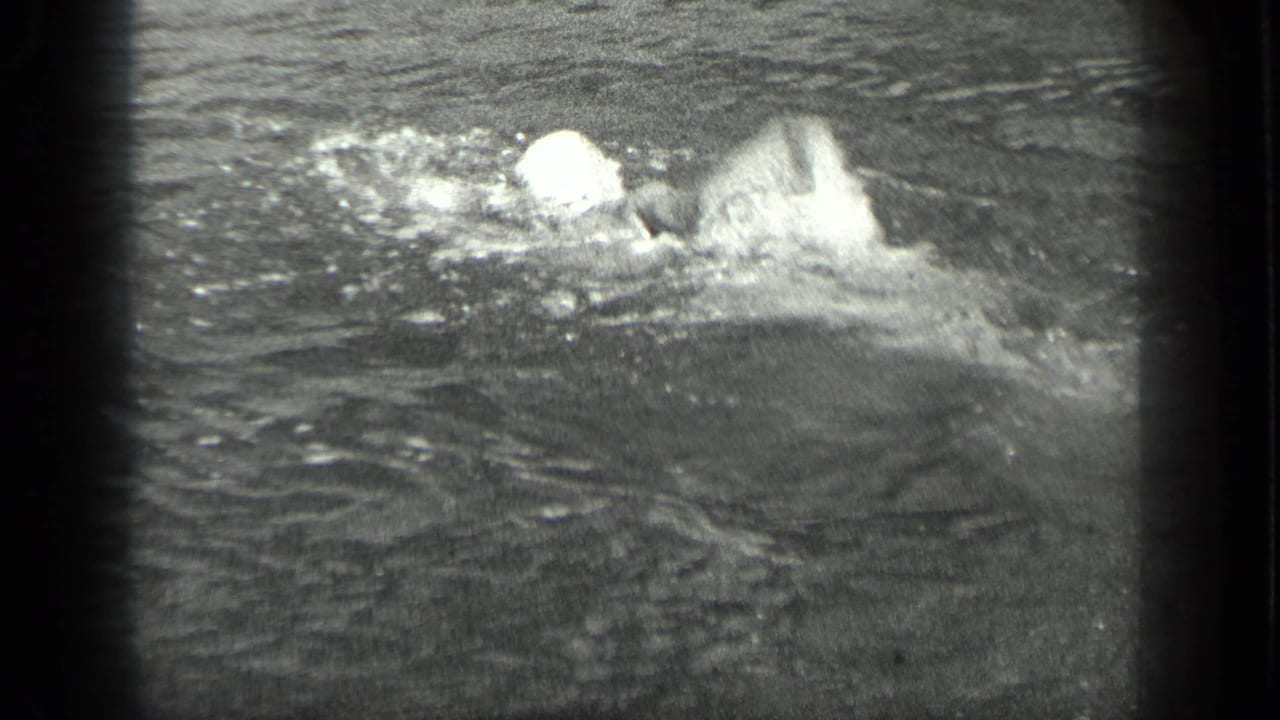 Swimmer in a bathing cap splashing through lake water.