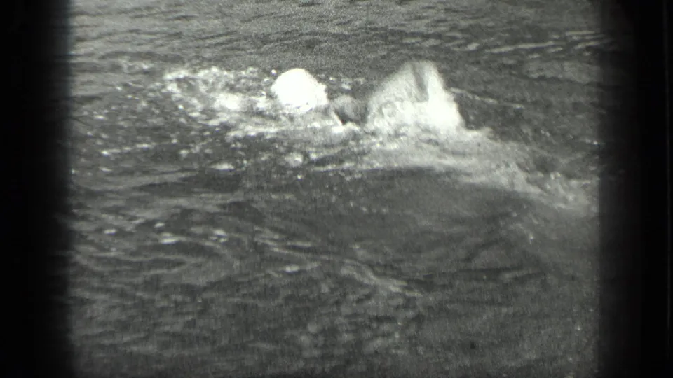 1939 Long Lake home-movie frame showing a capped swimmer moving through rippled lake water.