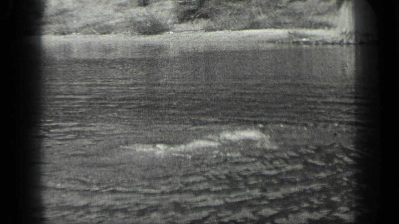 The swimmer remains partly submerged in the 1939 Long Lake scene, creating a low wake across the water.