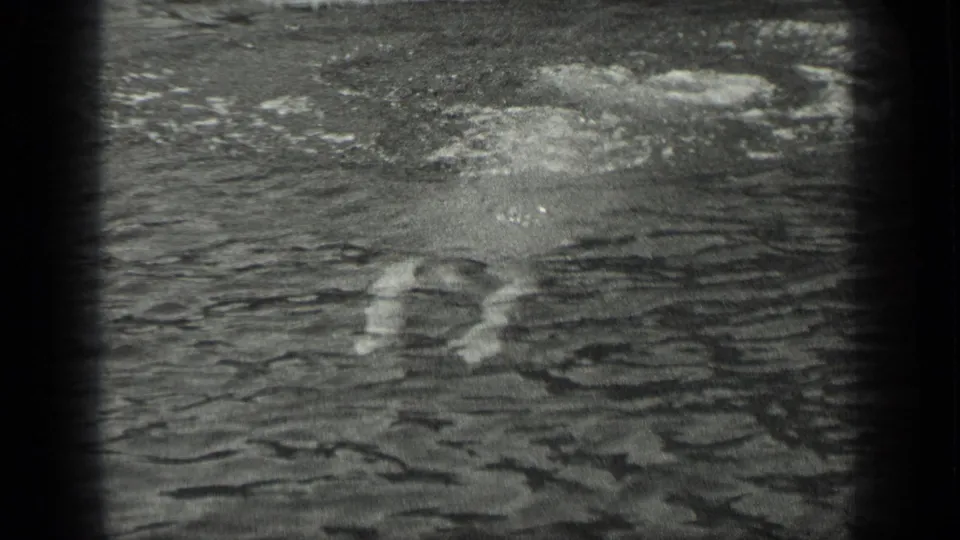 In 1939 Long Lake, Canada footage, a swimmer is partly submerged in rippled water near the camera frame edge.