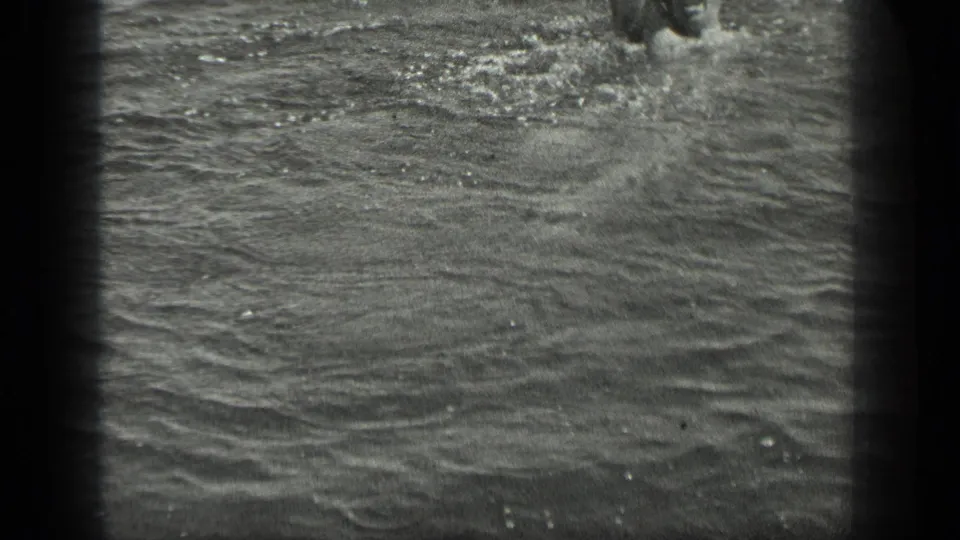 1939 Long Lake, Canada home-movie frame showing a swimmer partly cropped in rippling water with strong 8mm grain.