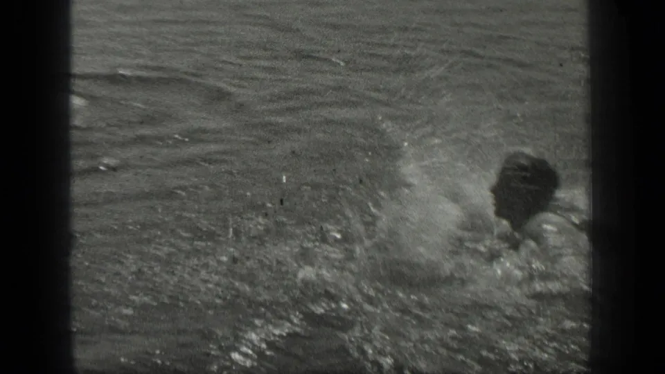 In the supplied Long Lake 1939 footage, a swimmer moves across rippled water while a splash breaks beside them.