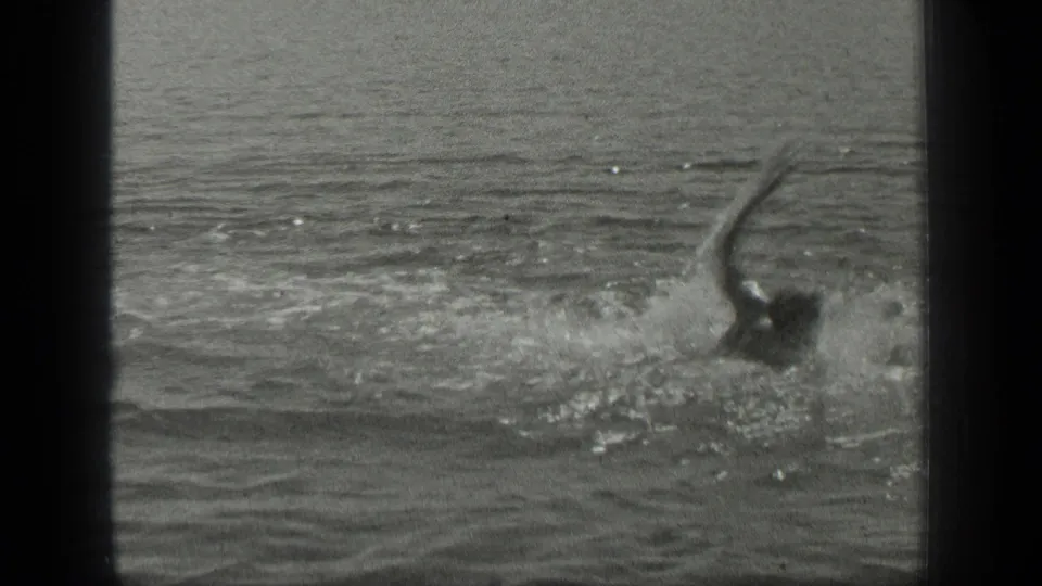 1939 Long Lake home-movie frame showing a swimmer partly visible, with one arm lifted above choppy water.