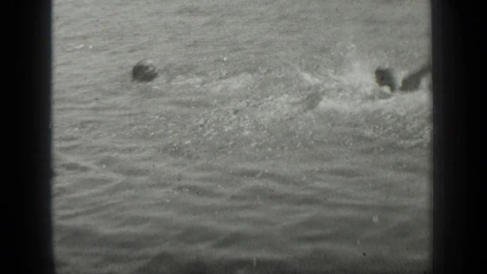 A grainy 1939 Long Lake, Canada frame shows swimmers partly submerged, with spray and churned water spreading across the lake surface.