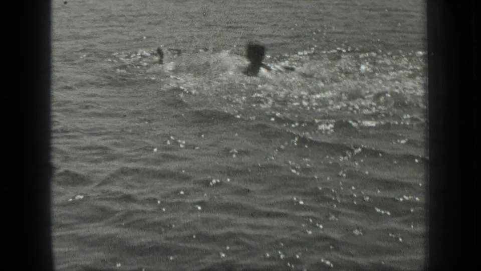 In this 1939 Long Lake, Canada home-movie frame, multiple swimmers appear as small dark heads amid sparkling ripples and splashing water.
