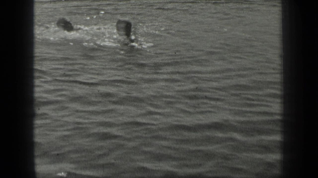 1939 Long Lake home-movie frame showing two swimmers close together amid small splashes and ripples.