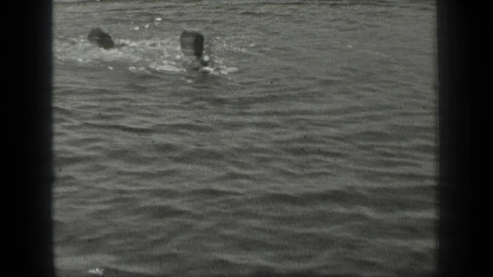 1939 Long Lake home-movie frame showing two swimmers close together amid small splashes and ripples.