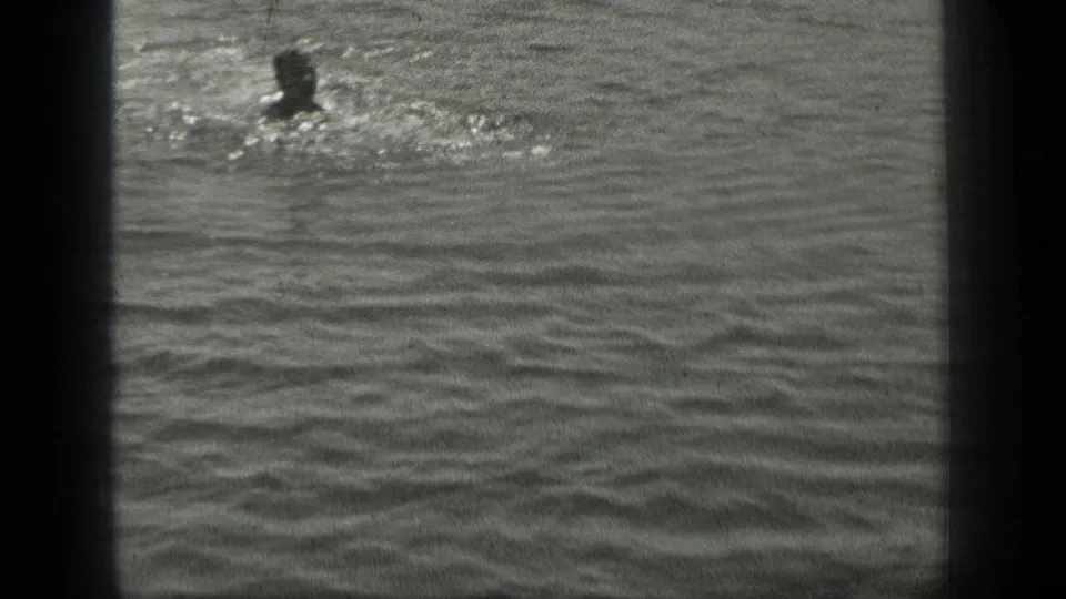 Long Lake, Canada frame with a swimmer partly visible near surface splashes in grainy black-and-white water.