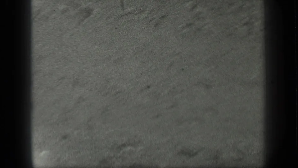 1939 8mm home-movie frame showing a soft, grainy Long Lake water view with faint ripples and sandy bottom texture.