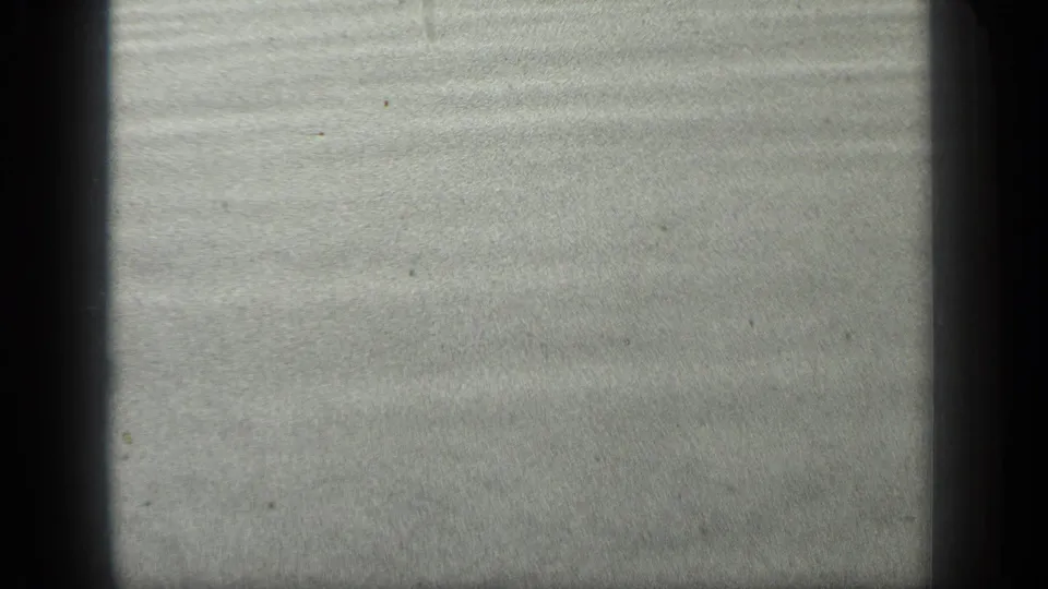 Close 8mm view of Long Lake wet sand or shallow water, showing horizontal ripple lines and visible film wear.