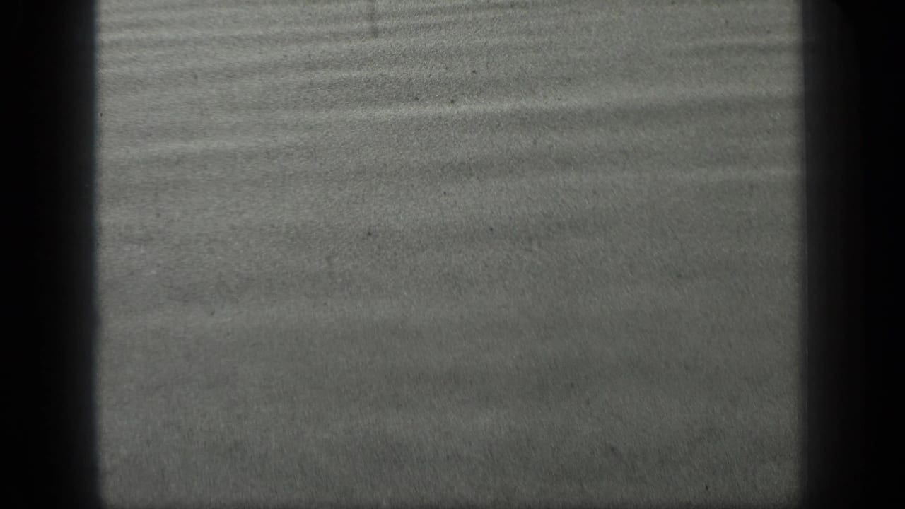 Dark grey rippling water surface with soft film grain and edge shadowing.