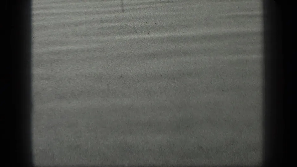 1939 Long Lake, Canada 8mm frame showing a dark grey water surface with gentle ripples, grain, and shadowed film edges.
