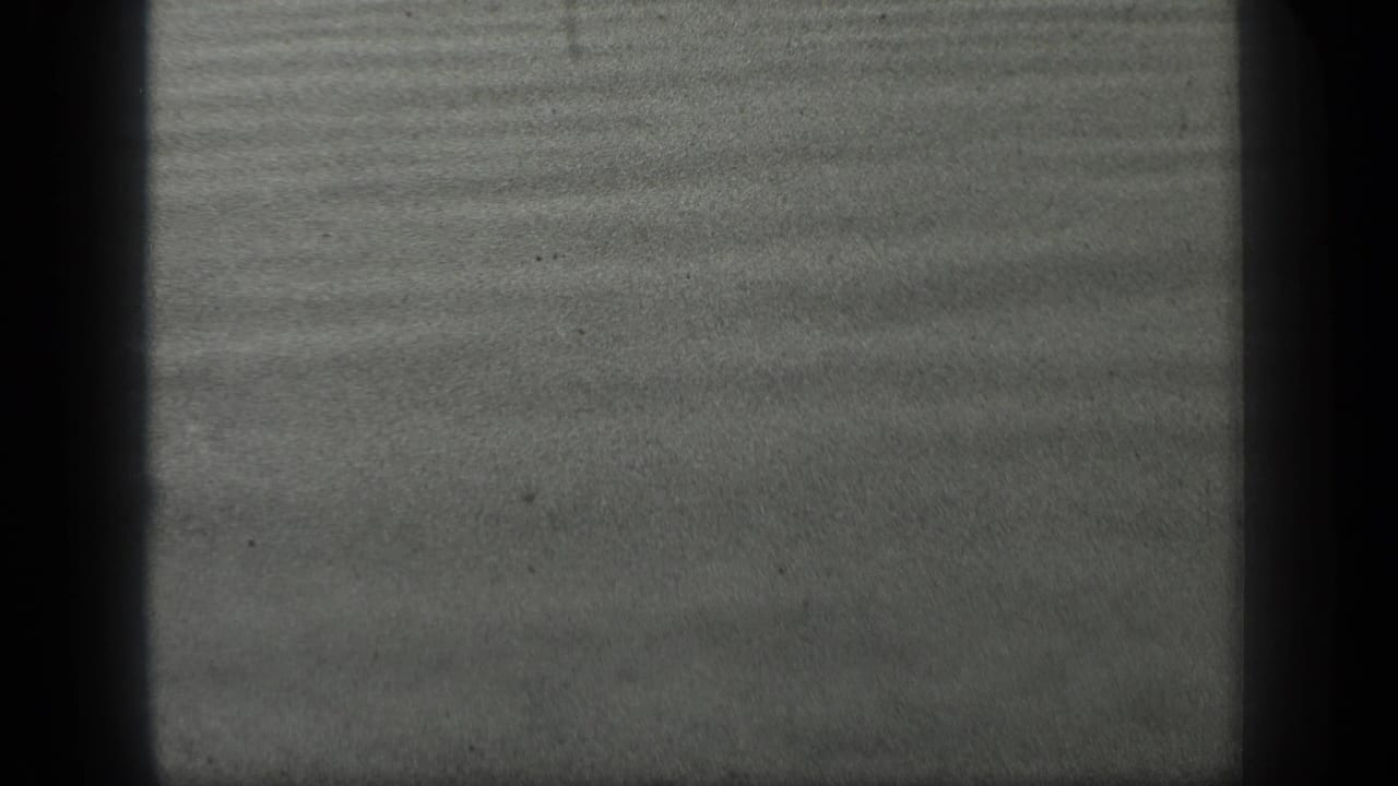 Smooth grey water with horizontal ripple bands and dark vertical edge shadows.