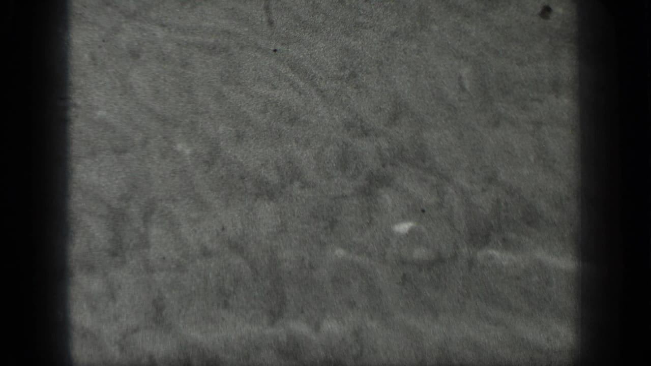 1939 Long Lake, Canada 8mm frame showing grey water texture with faint swirling ripples, specks, and darkened film edges.