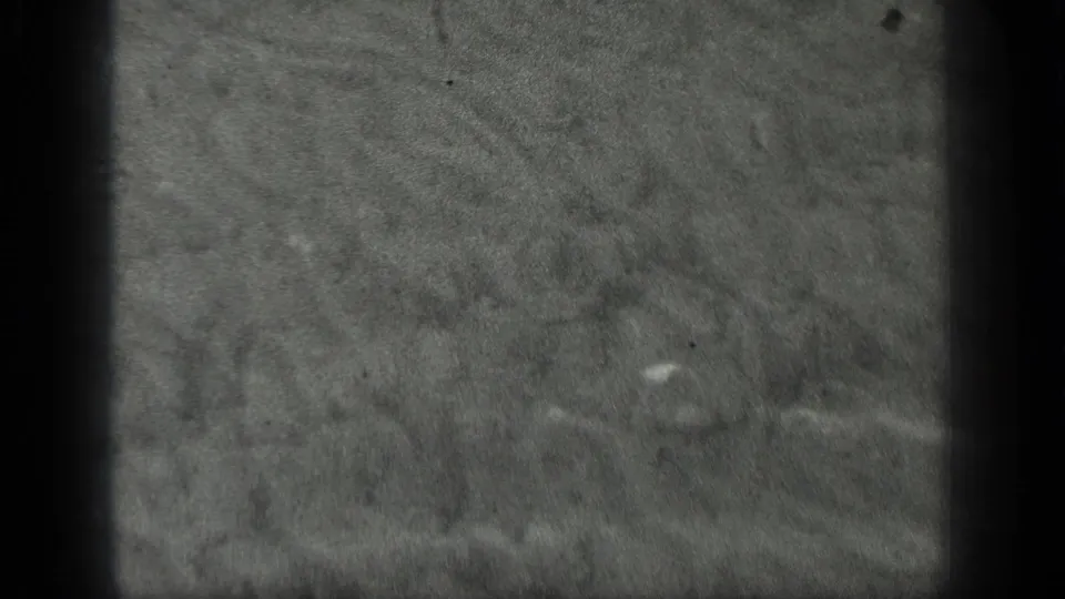 1939 Long Lake, Canada 8mm frame showing grey water texture with faint swirling ripples, specks, and darkened film edges.