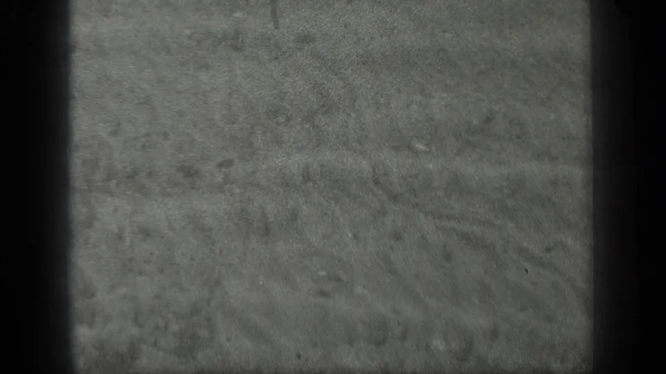 1939 Long Lake, Canada 8mm frame showing clear shallow water over sand with scattered small stones and visible gate edges.