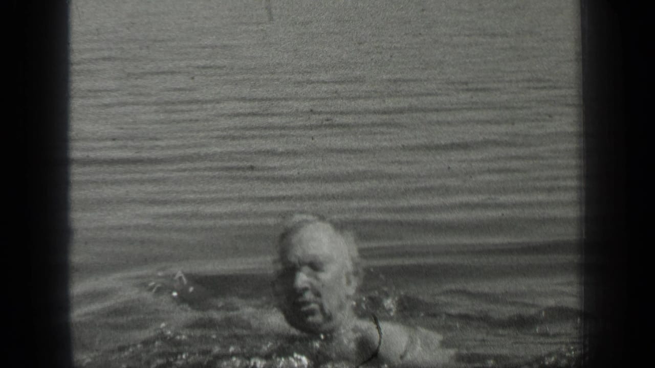 An older swimmer crosses the frame in Long Lake, Canada, with only water and ripples around him.