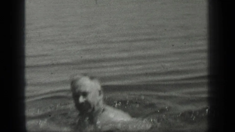 Adult man swims near the camera in Long Lake, Canada, in black-and-white 1939 8mm home-movie footage.