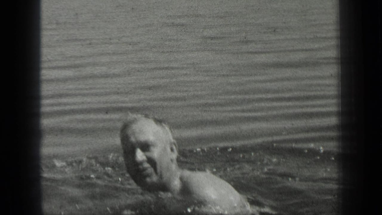 Adult man swims in Long Lake, Canada, in 1939 black-and-white 8mm home-movie footage, with his head and shoulders above the water.