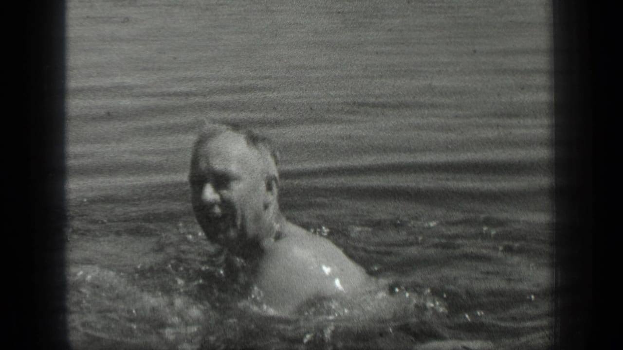 Man in the water facing the camera with ripples across the lake surface.