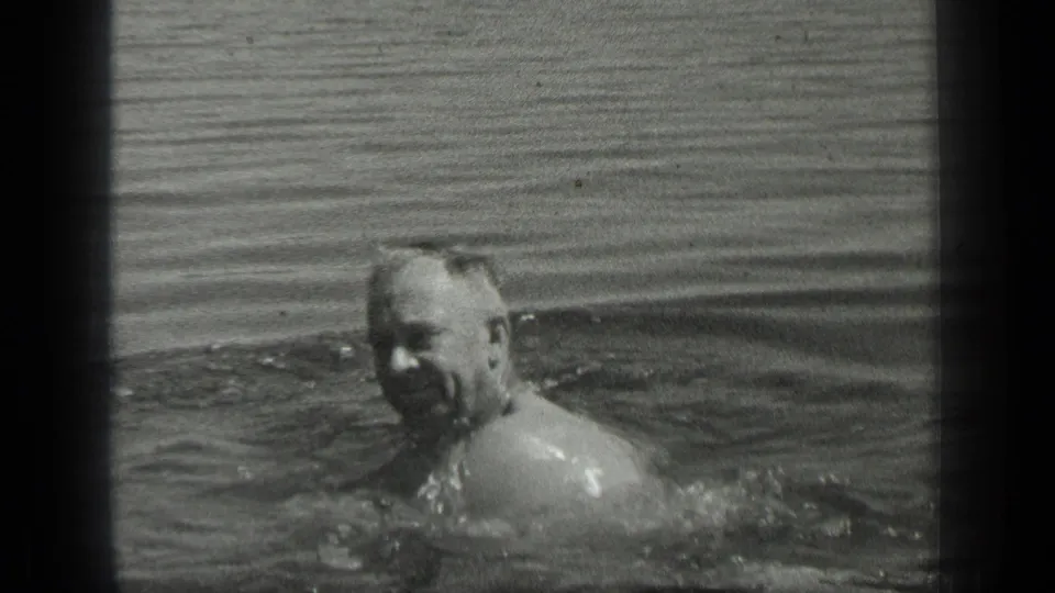 The adult swimmer appears to smile while moving through Long Lake, Canada, in a grainy 1939 8mm home movie frame.