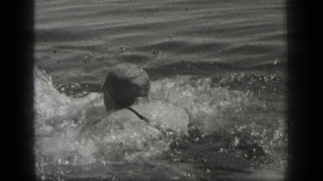 The man swims away from the camera in Long Lake, Canada, with splashing water and his back visible in 1939 black-and-white 8mm footage.