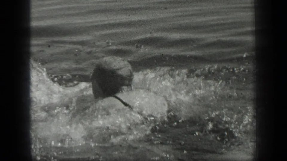 The man swims away from the camera in Long Lake, Canada, with splashing water and his back visible in 1939 black-and-white 8mm footage.