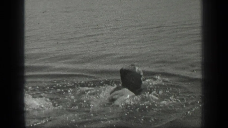 In 1939 Long Lake, Canada footage, a swimmer moves through calm water with splashes and a dark 8mm frame edge visible.
