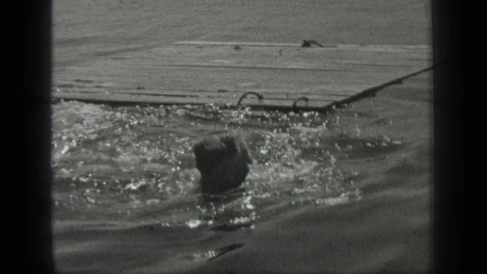 In 1939 Long Lake, Canada footage, a swimmer's head is visible amid choppy water near a shore or dock edge.