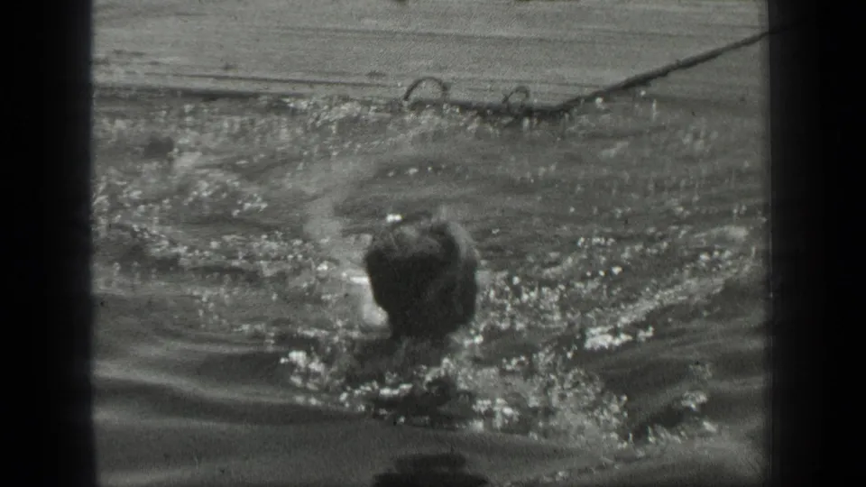 The swimmer moves through bright, splashing Long Lake water, with the head and shoulders partly visible.