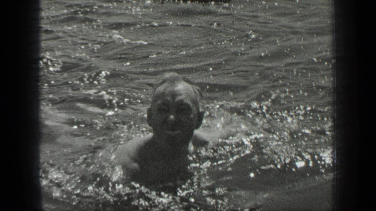 A swimmer faces the camera in 1939 Long Lake footage, with water splashing around the upper body.