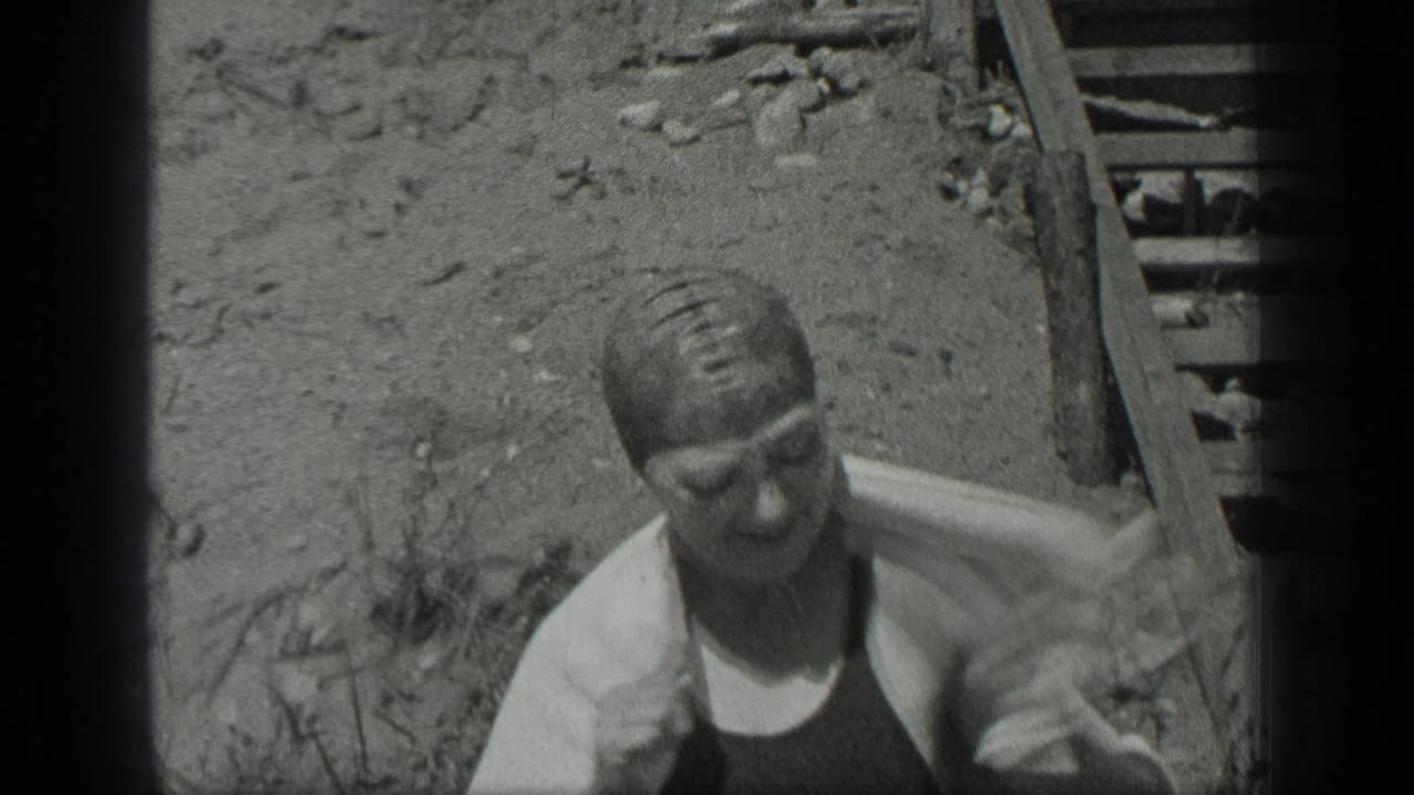 The woman towels off by the shoreline steps at Long Lake, Canada, in black-and-white 8mm footage from 1939.