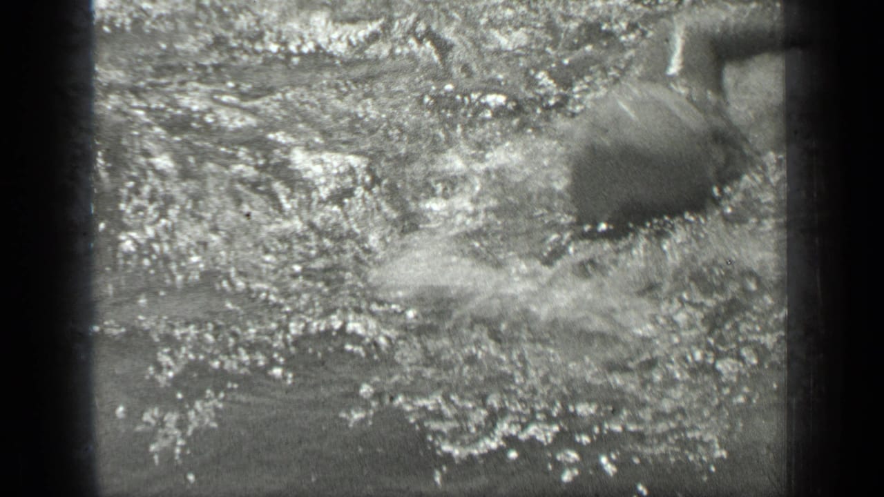 A swimmer moves through sunlit lake water at Long Lake, Canada, with heavy splash, glare, and soft 8mm motion blur.