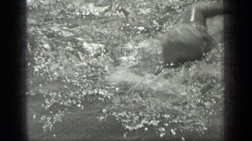 A swimmer moves through sunlit lake water at Long Lake, Canada, with heavy splash, glare, and soft 8mm motion blur.