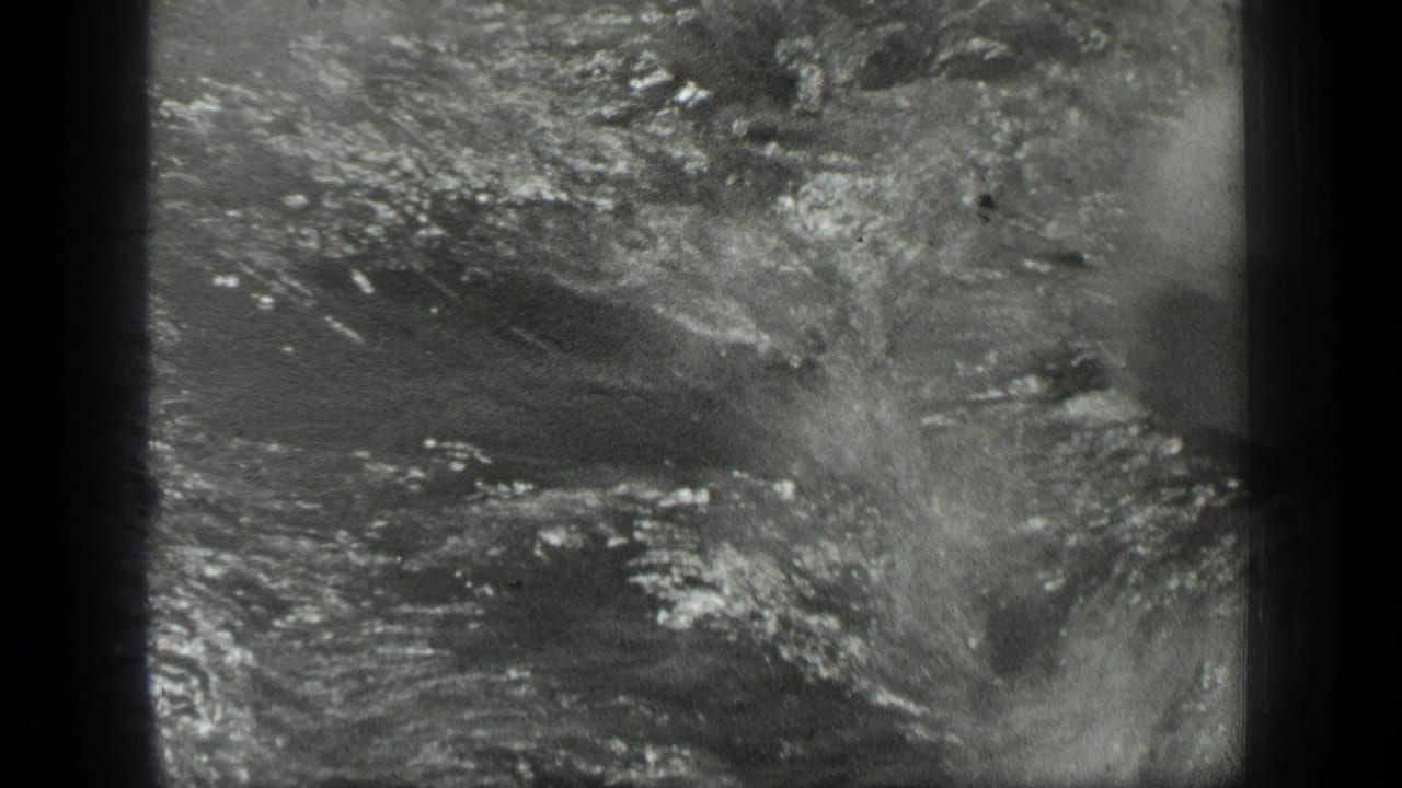 1939 Long Lake home-movie frame showing a woman swimming as splashes and ripples fill the shallow water.