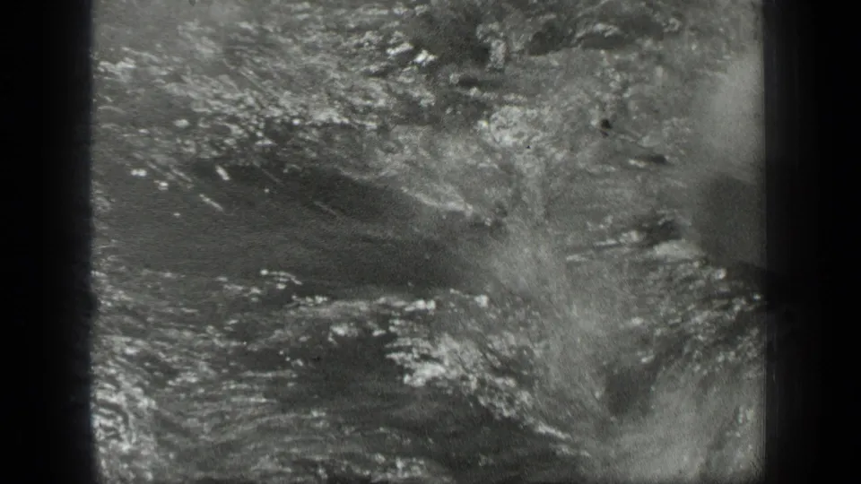 1939 Long Lake home-movie frame showing a woman swimming as splashes and ripples fill the shallow water.
