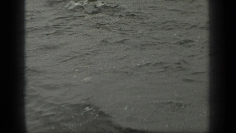 Final 8mm frame from Long Lake showing textured water and ripples, with the swimmers mostly out of view.