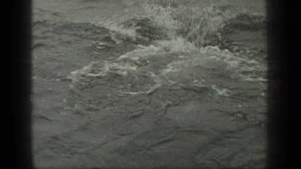 A burst of lake water fills the frame as the swimmer moves out of clear view during the Long Lake home-movie scene.